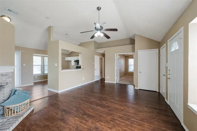 a view of an empty room with window and wooden floor