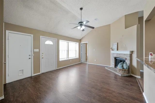 an empty room with fireplace wooden floor and windows