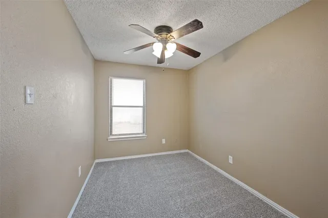 an empty room with window and chandelier fan