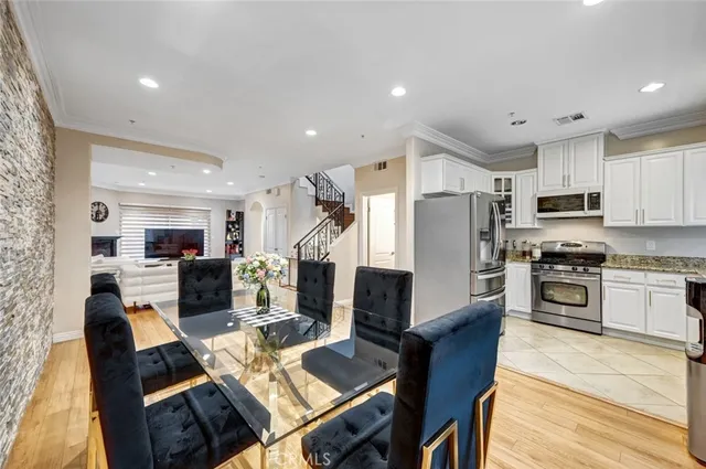 a open kitchen with stainless steel appliances kitchen island granite countertop a refrigerator a stove top oven a sink dishwasher and white cabinets with wooden floor