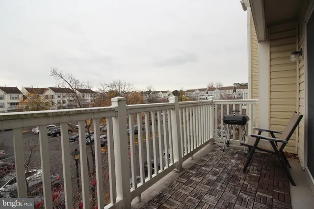 a view of a balcony with wooden chairs and iron fence