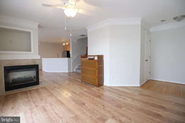 a view of a livingroom with a fireplace a ceiling fan and wooden floor