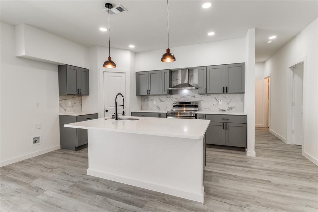 3108 Delafield Lane Dallas, TX 75227 - Photo 11 of 30 a large kitchen with kitchen island a stove a sink a center island and a wooden floor
