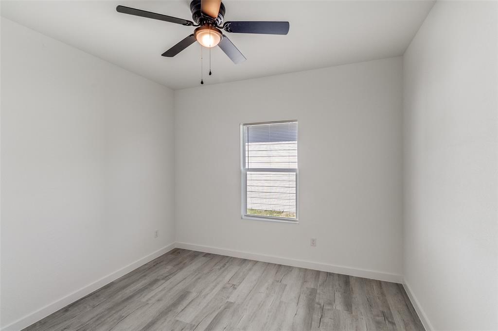 3108 Delafield Lane Dallas, TX 75227 - Photo 22 of 30 an empty room with wooden floor ceiling fan and windows