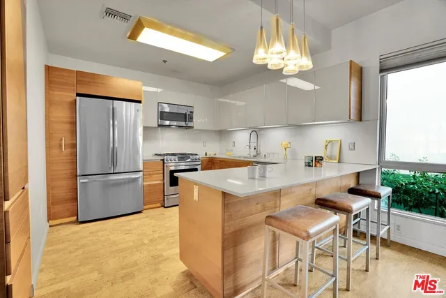 a kitchen with kitchen island granite countertop a stove a refrigerator a sink a dining table and chairs with wooden floor