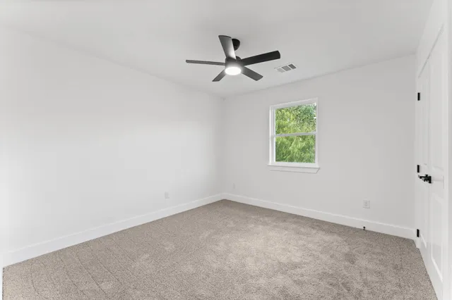 an empty room with a window and a fan