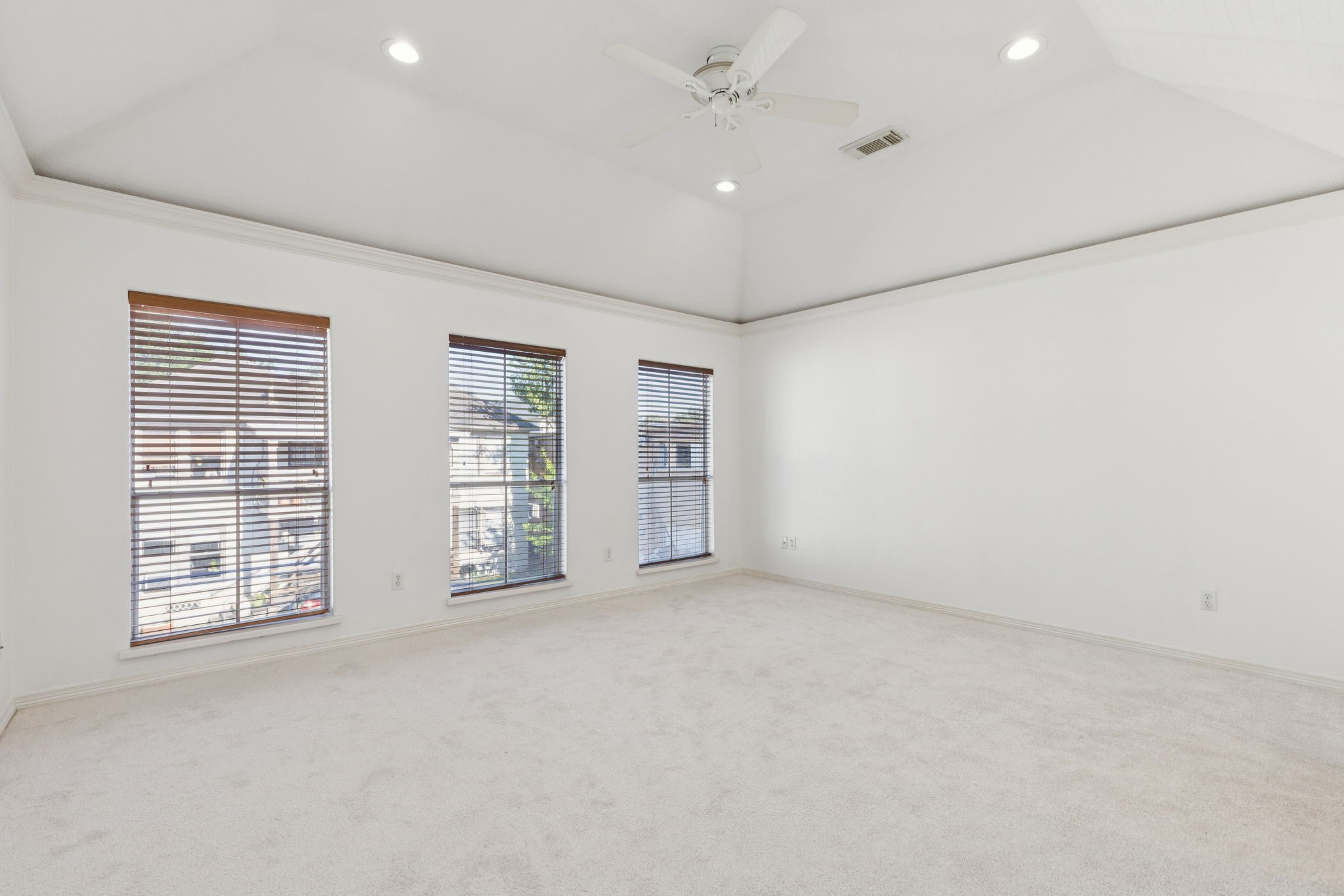 4916 Travis Street Houston, TX 77004 - Photo 13 of 26 This inviting primary bedroom offers ample space and comfort, featuring newly installed, plush carpeting that provides a warm and inviting feel underfoot. The room boasts impressive high ceilings, creating an open and airy atmosphere. For added privacy and light control, the windows are fitted with functional blinds.