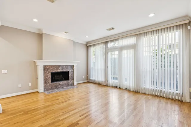 a view of an empty room with wooden floor fireplace and a window