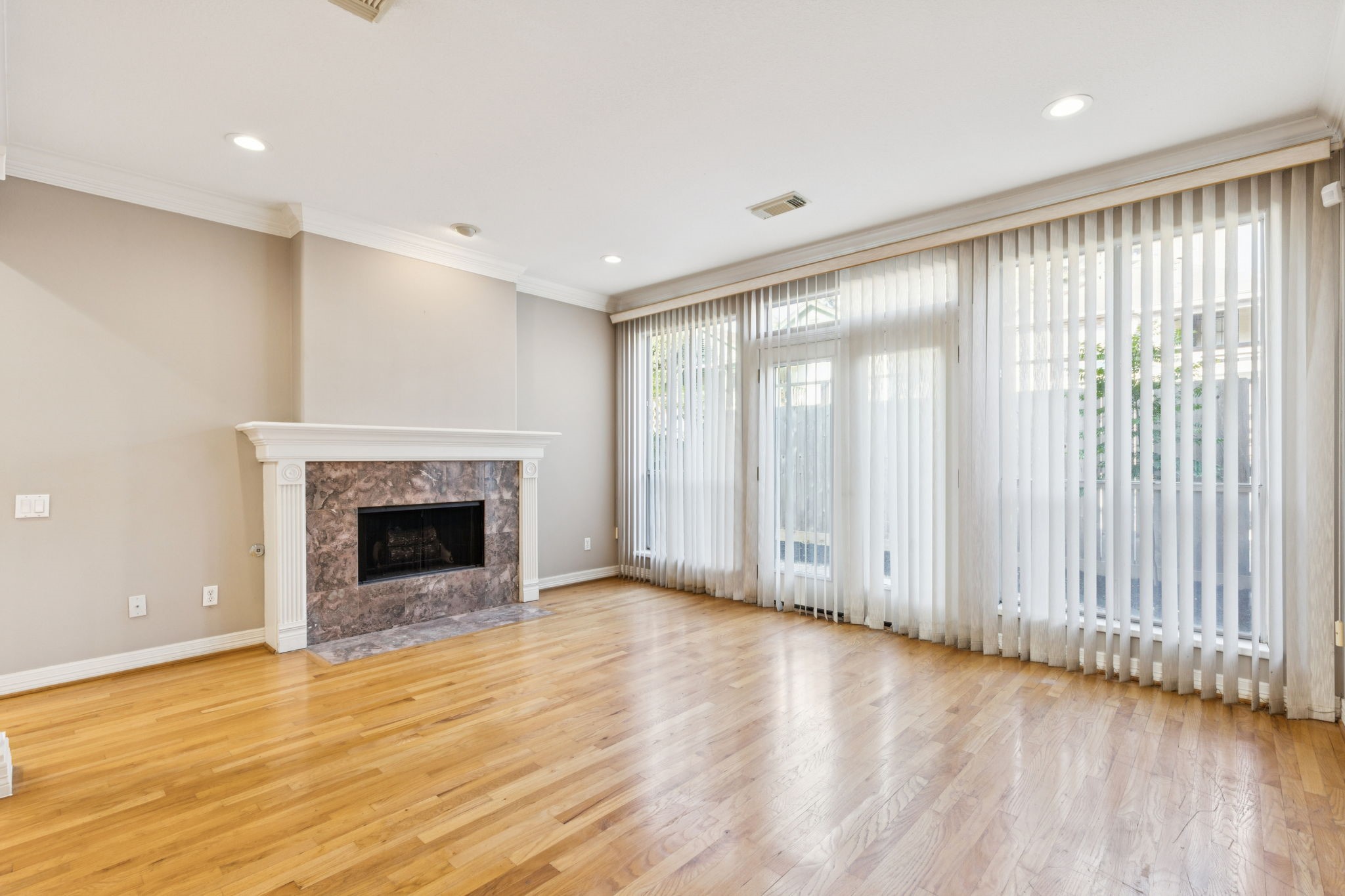 4916 Travis Street Houston, TX 77004 - Photo 5 of 26 Natural light floods the living room, enhanced by nice high ceilings and hardwood floors. A gas log fireplace adds warmth, and the recently painted walls create a fresh, inviting atmosphere. Doors lead to a lovely backyard area.