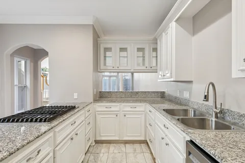 a kitchen with granite countertop a sink stove and cabinets