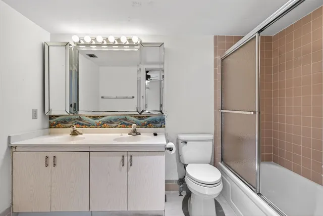 a bathroom with a shower sink vanity mirror and toilet