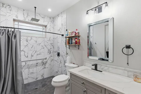 a bathroom with a sink a toilet and shower