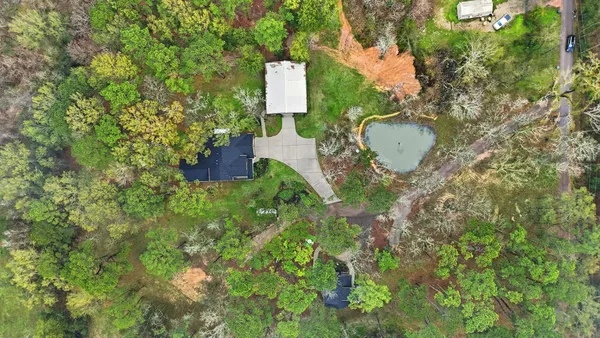 an aerial view of residential house with outdoor space and trees all around