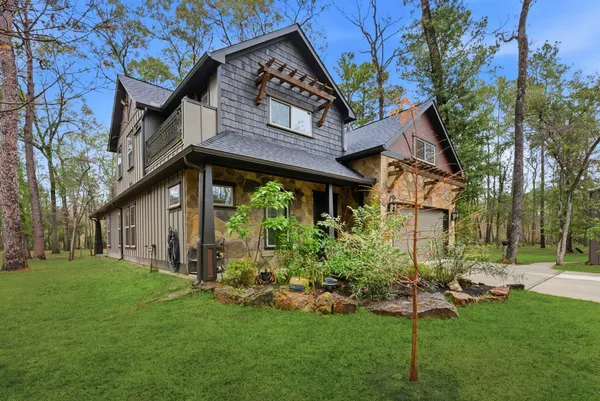 a view of a house with a big yard plants and large tree