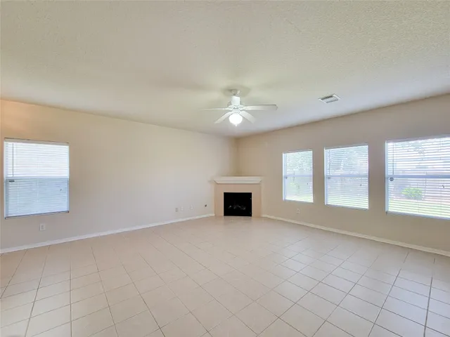 an empty room with windows and fireplace