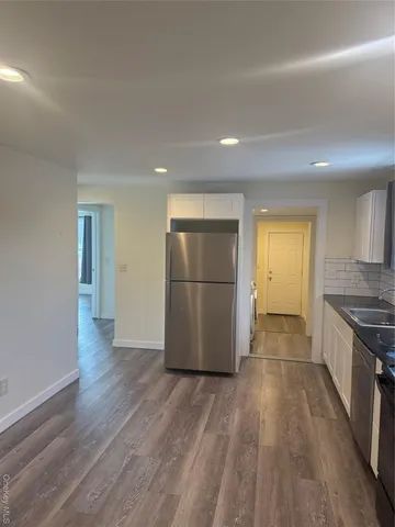 a view of a kitchen with a wooden floor and stainless steel appliances