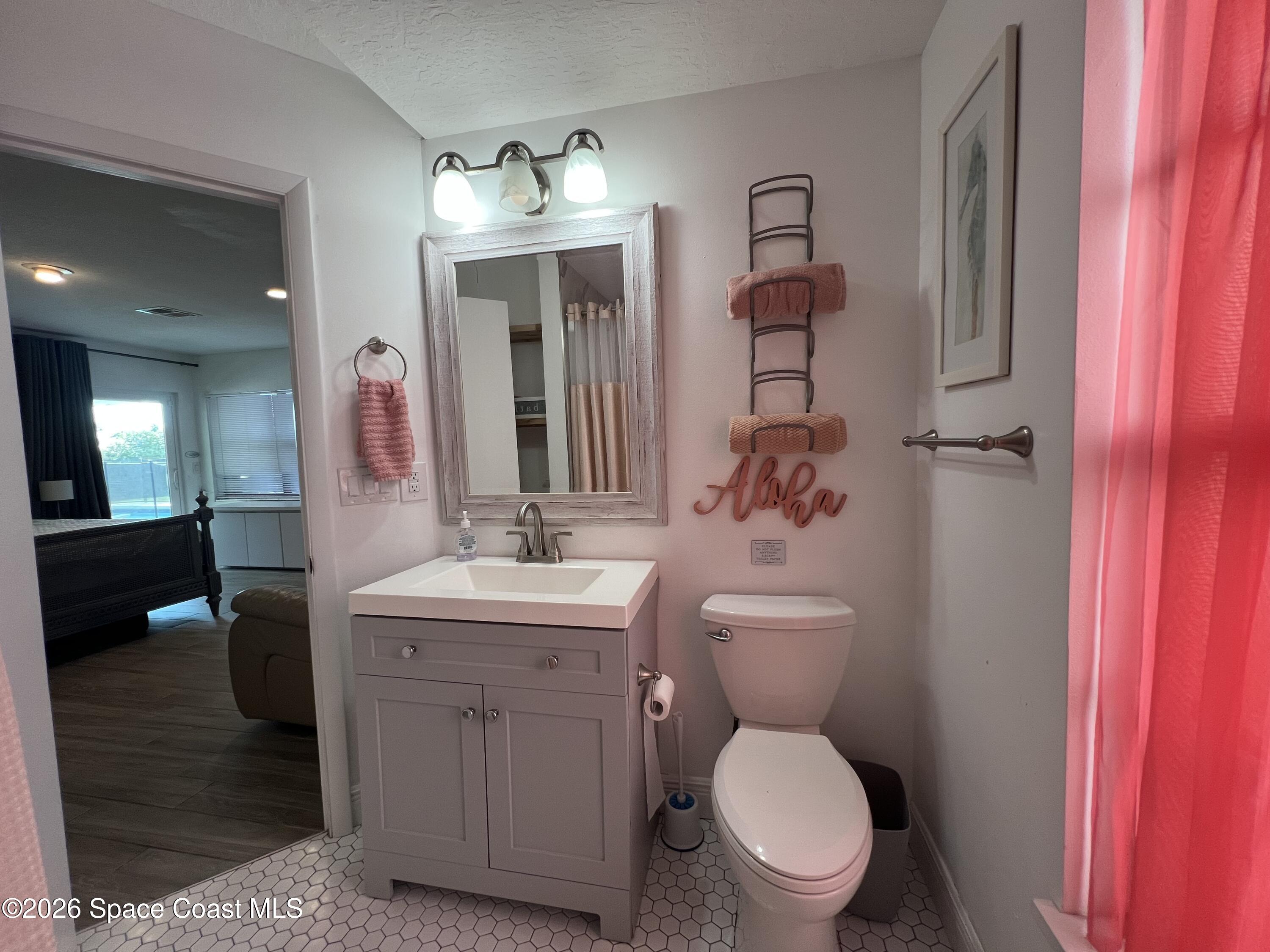 120 Boca Ciega Road Cocoa Beach, FL 32931 - Photo 22 of 23 a bathroom with a toilet a sink and mirror