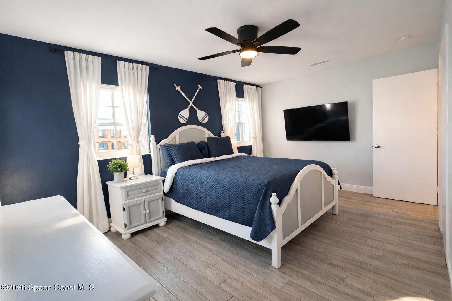120 Boca Ciega Road Cocoa Beach, FL 32931 - Photo 10 of 23 a living room with a bed furniture flat screen tv and a large window