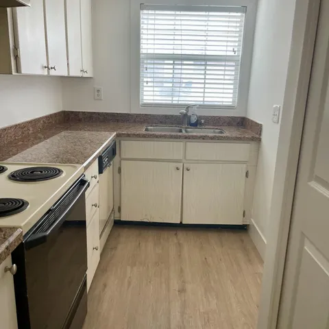 a view of a kitchen with a sink a window and cabinets