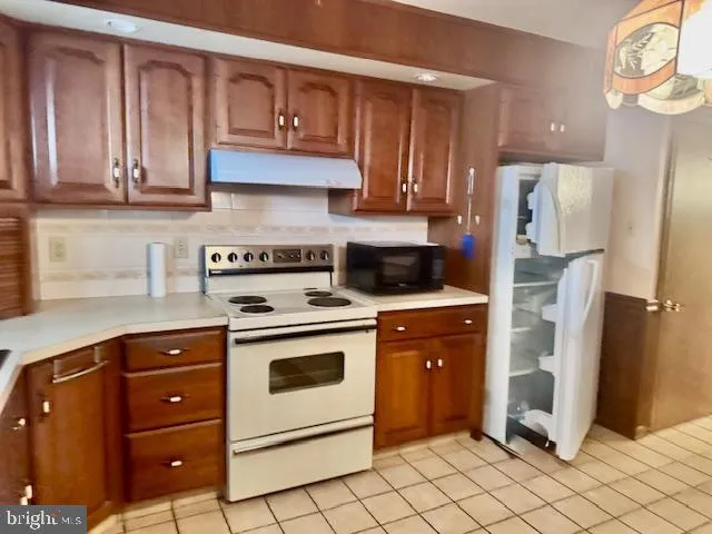 a kitchen with stainless steel appliances granite countertop a refrigerator a stove and a sink