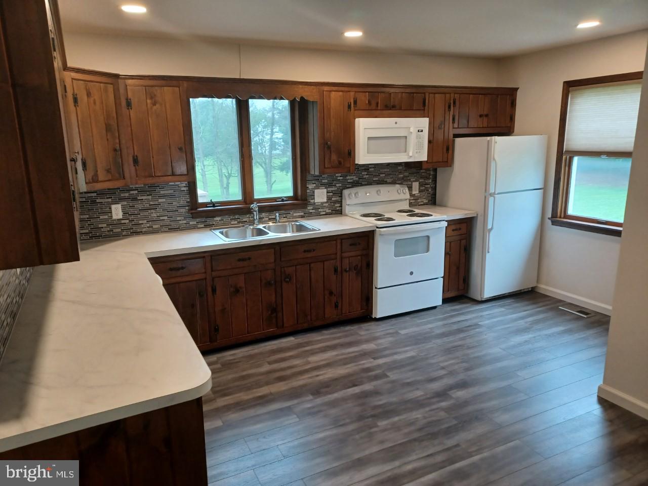1525 Yardley Newtown Road, Unit 1 Morrisville, PA 19067 - Photo 3 of 14 a large kitchen with wooden floor a sink a window and stainless steel appliances