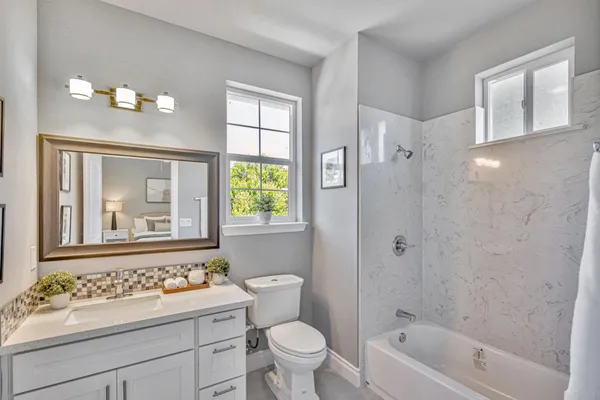 a bathroom with a sink a toilet a shower a mirror and a bathtub