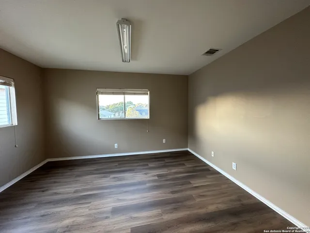 an empty room with wooden floor and windows