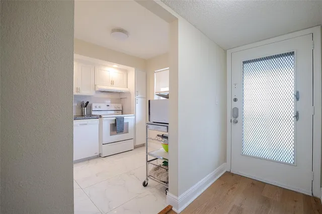 a kitchen with stainless steel appliances granite countertop white cabinets and a window
