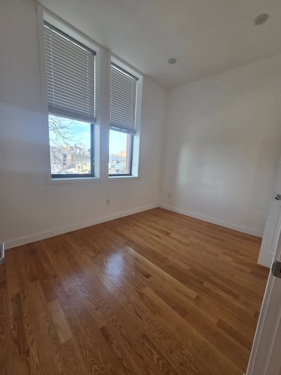 64 Market Street, Unit 303 Lynn, MA 01901 - Photo 8 of 12 an empty room with wooden floor and windows
