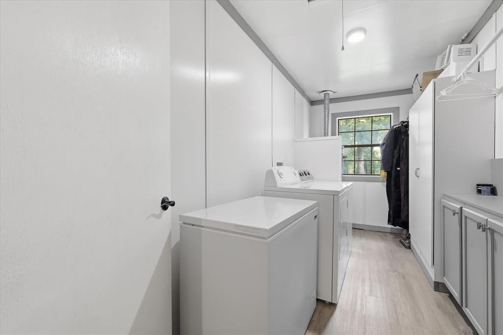 237 Brenda Lane Gainesville, TX 76240 - Photo 24 of 40 Utility room featuring wood-finish flooring, white paneled walls, and a large window with exterior foliage