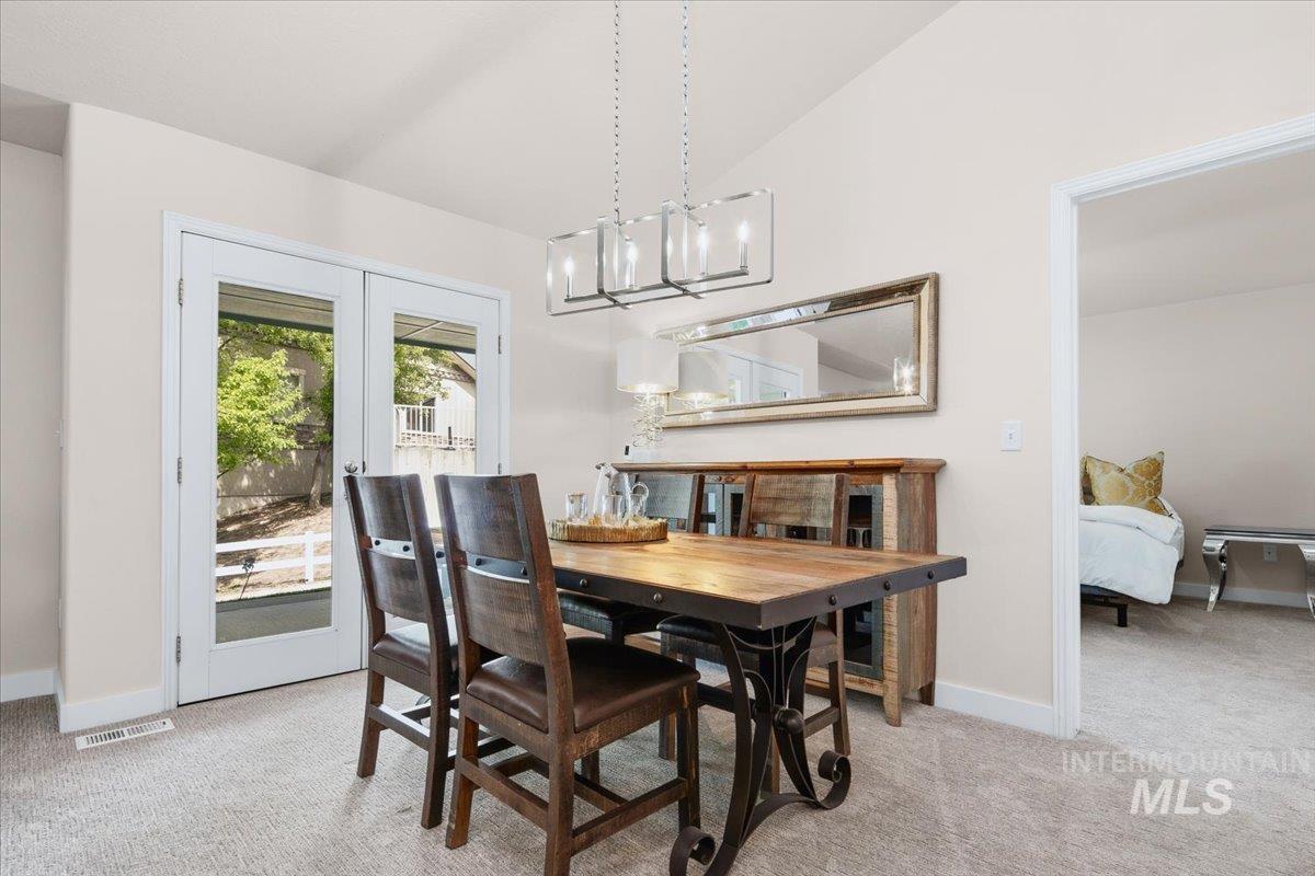 725 North Eagle Road Eagle, ID 83616 - Photo 15 of 45 Dining area featuring vaulted ceilings, light-toned carpeting, and a contemporary linear chandelier