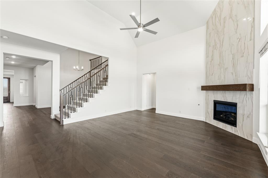 1145 Hitching Post Way Oak Point, TX 75068 - Photo 17 of 39 a view of an empty room with wooden floor a ceiling fan and a fireplace