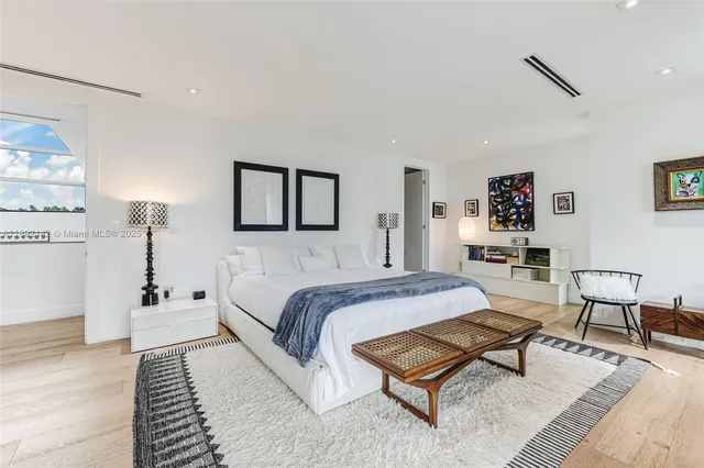 a spacious bedroom with a bed a rug and a wooden floor