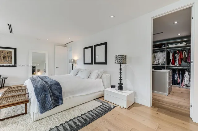 a spacious bedroom with a bed a mirror and painting on the wall