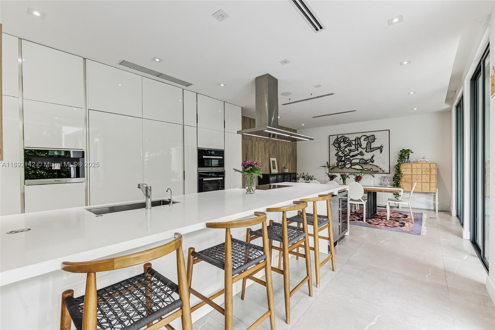 445 Ridgewood Road Key Biscayne, FL 33149 - Photo 10 of 35 a kitchen with stainless steel appliances kitchen island granite countertop a table and chairs in it