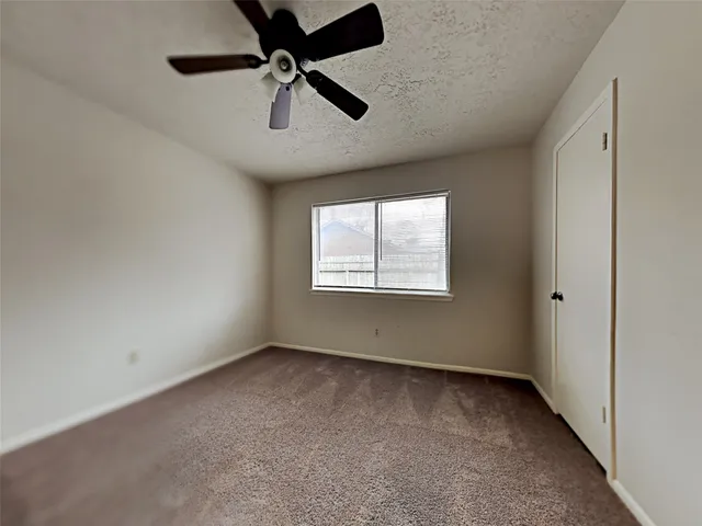 an empty room with a ceiling fan and carpet