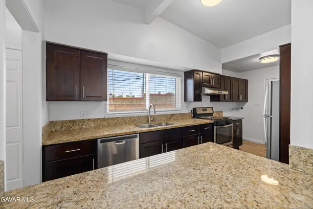 a kitchen with stainless steel appliances granite countertop a sink a stove and a wooden floors
