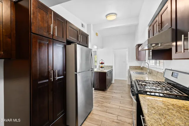 a kitchen with stainless steel appliances granite countertop wooden cabinets a stove top oven a sink and dishwasher