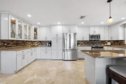 a kitchen with stainless steel appliances granite countertop a refrigerator and a stove top oven