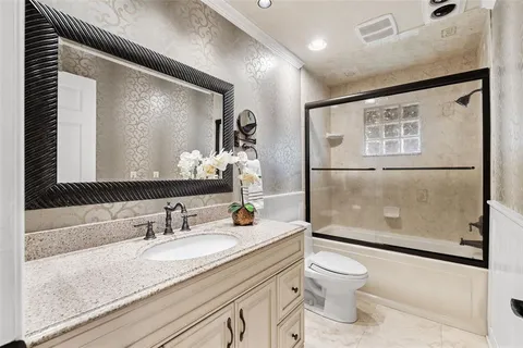a bathroom with a granite countertop sink toilet and shower