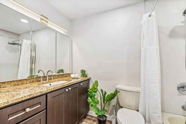 a bathroom with a granite countertop sink a mirror and a toilet