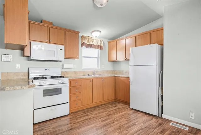 a kitchen with a refrigerator a stove a microwave and wooden floor