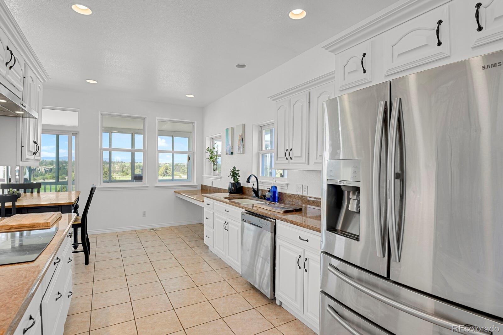 897 East Rim Road Franktown, CO 80116 - Photo 9 of 32 a kitchen with stainless steel appliances a refrigerator sink and cabinets