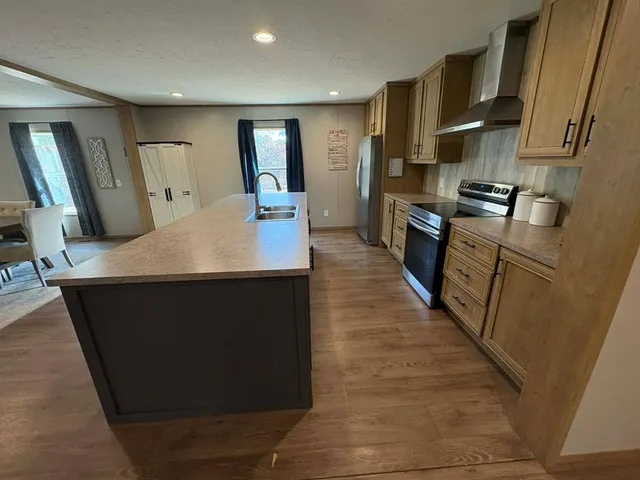 a kitchen with stainless steel appliances granite countertop a refrigerator a stove and a sink