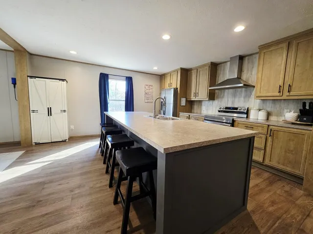 a kitchen with kitchen island granite countertop wooden floors and refrigerator