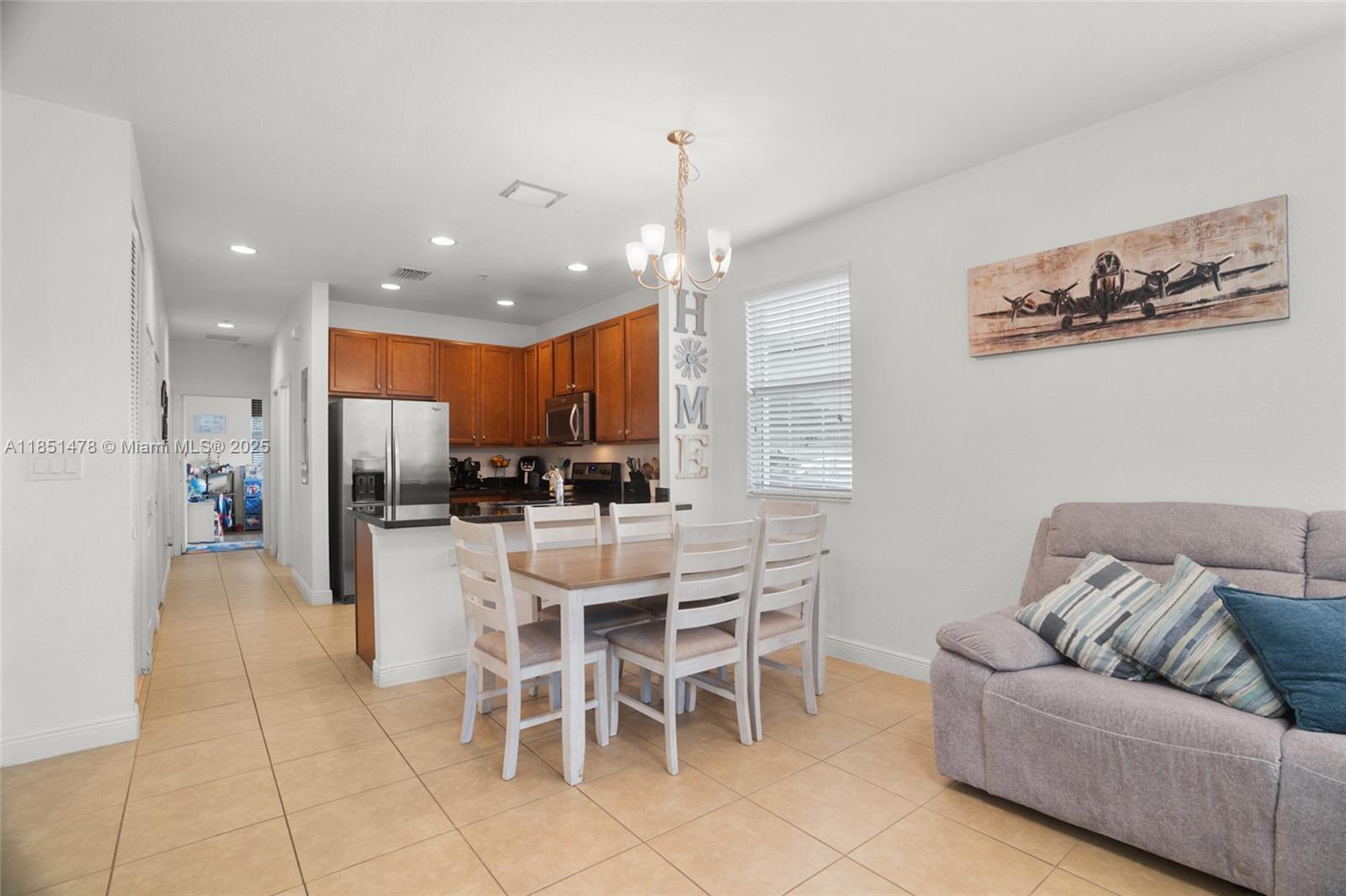14774 Southwest 10th Street, Unit 10502 Pembroke Pines, FL 33027 - Photo 11 of 40 a living room with furniture a kitchen view and a chandelier