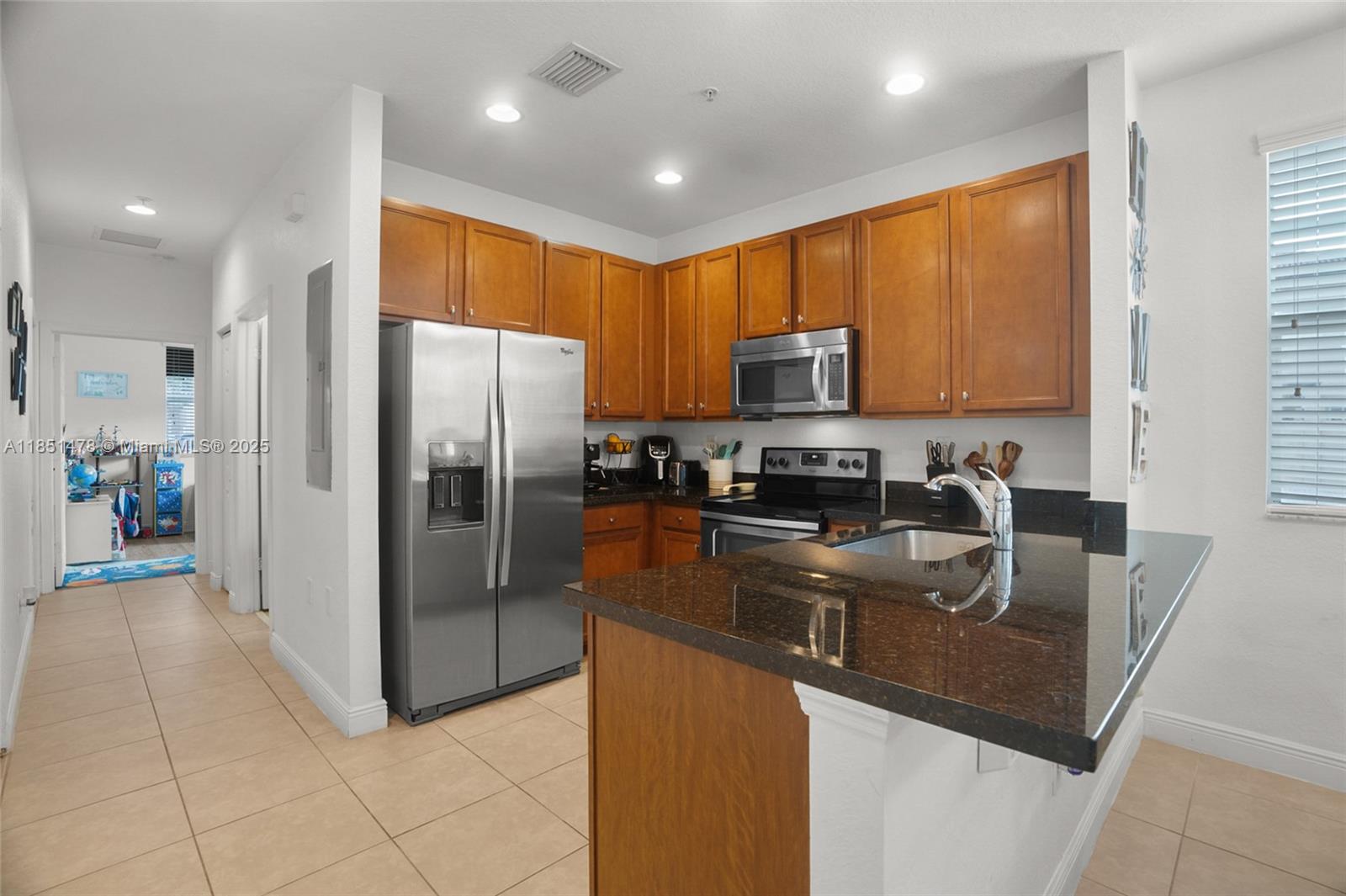 14774 Southwest 10th Street, Unit 10502 Pembroke Pines, FL 33027 - Photo 13 of 40 a kitchen with stainless steel appliances granite countertop a refrigerator a stove a sink a oven with a dining table and chairs