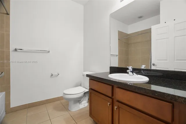 a bathroom with a granite countertop sink a toilet and a mirror