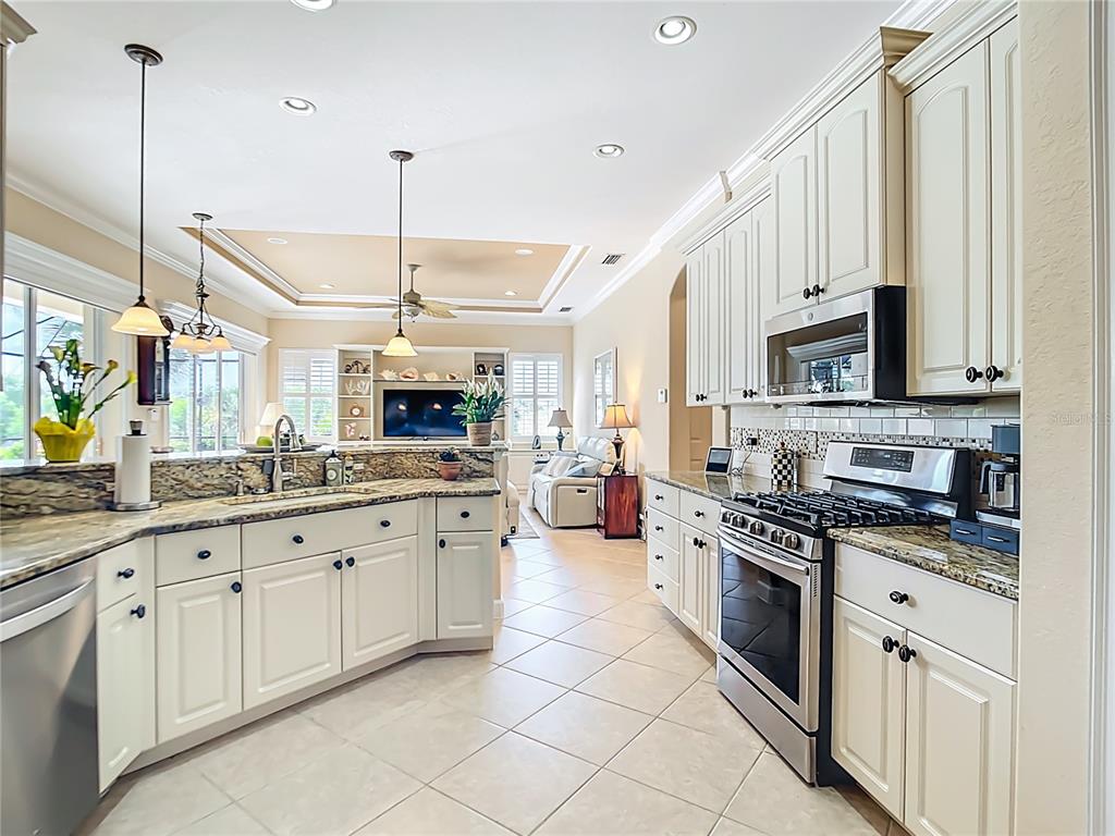 114 Rimini Way North Venice, FL 34275 - Photo 9 of 54 a large kitchen with granite countertop a stove a sink dishwasher and a microwave oven with white cabinets