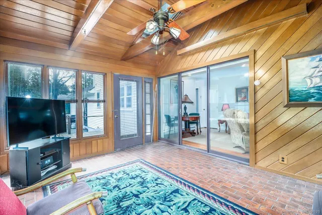 a living room with furniture a flat screen tv and a floor to ceiling window